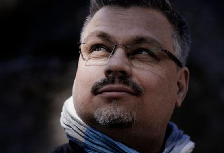 Kuvassa on Tommi Kinnunen vaaleassa kaulaliinassa kasvokuvassa.