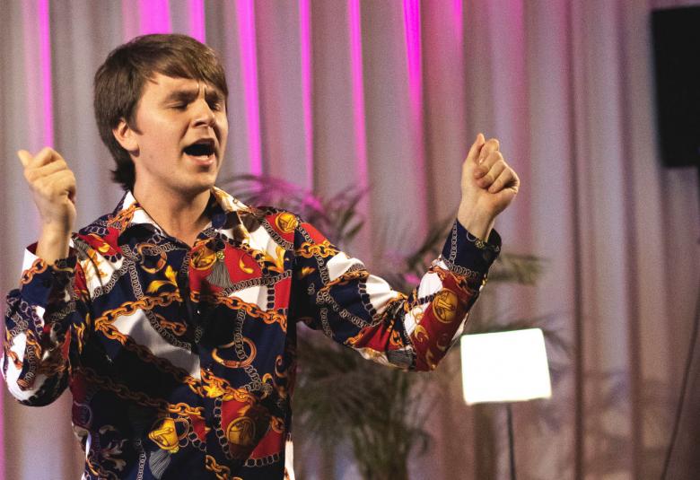 Kuvassa on Elias Husgafvel esiintymässä kirjavassa takissa.