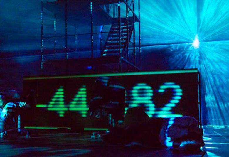 Kuvassa on näyttämöä, joka on sävyltään tumman sininen ja telineissä on suuri digitaalinen näyttö, jossa on numerot -44 ja 82.