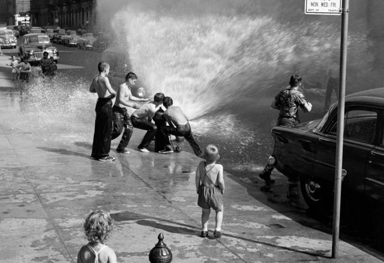 Kuvassa on poikia leikkimässä New Yorkissa kadulla suihkuavalla vesipostilla. 