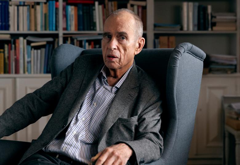 uvassa on Jörn Donner istumassa nojatuolissaan ja takanaan kirjahylly.