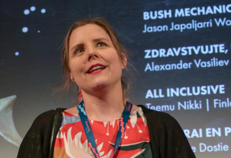 Kuvassa on Tampereen Filmijuhlien toiminnanjohtaja Laura Laaksonen ja hän katsoo yläviistoon. Taustalla on viime vuoden festivaalin tekstejä.