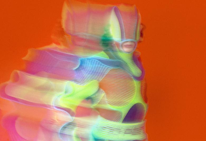 Kuvassa on punaisella pohjalla vihreän keltaisella avaruuspuvussa olevan hahmo. Kuva  on puolivartalokuva.