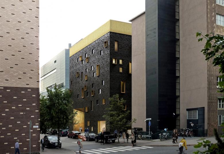 Kuvassa on uusi rakennus Arabianrannassa kuvattuna kadunkulmasta ja se on muiden moni kerroksisten rakennusten keskellä.  Rakennus väriltään musta.