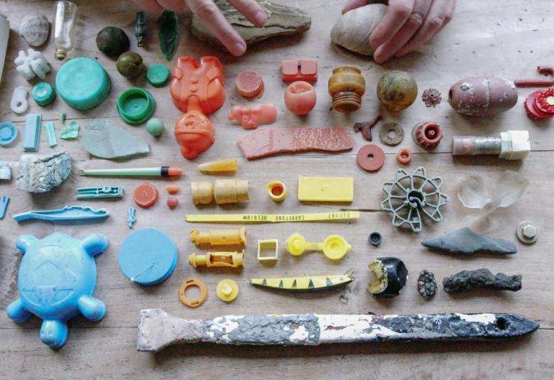 Kuvassa on harmaalla lattialla erilaisia pieniä muovisia esineitä.