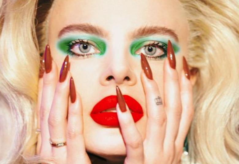 Kuvassa on Erika Vikmanin kasvokuva, jossa hänellä on vaaleat hiukset ja punaiset. 