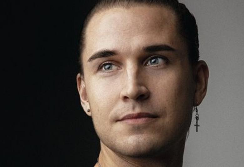 Kuvassa on Samuel Jyringin kasvokuva ja hänellä on oikeassa korvassaan ristikorvakoru. Tausta on vasemmalta musta ja oikealta harmaa.