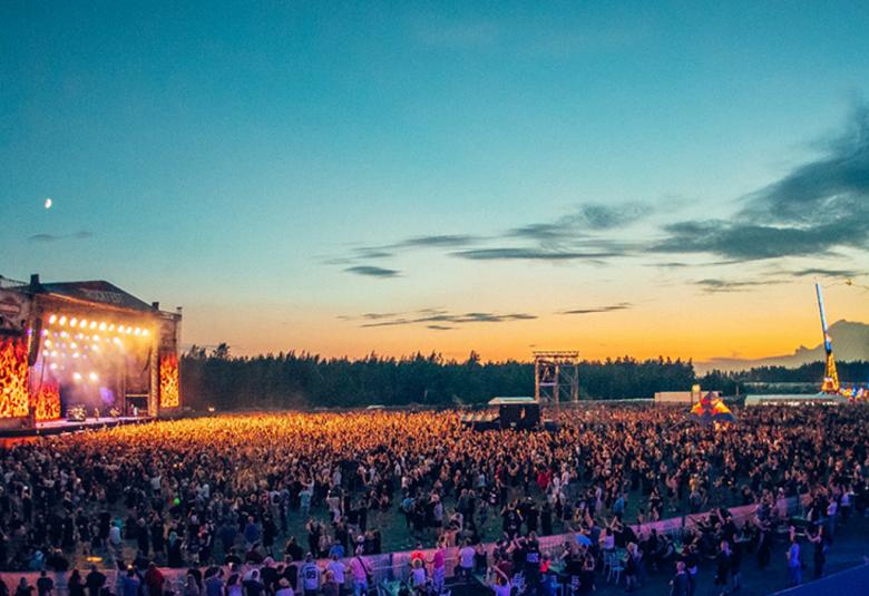 Kuvassa on Rockfestin areena ja yleisö iltavalistuksessa auringon laskiessa.