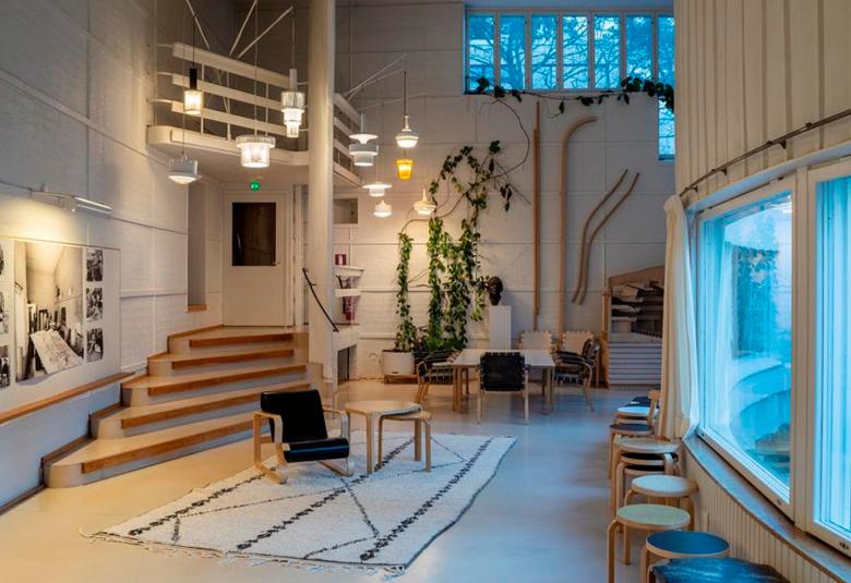 Kuvassa on Alvar Aallon ateljee ja siinä on etualalla tuoleja ja oikealla kaarevaa seinää. Vasemmalta lähtee muutama porras seuraavaan kerrokseen.