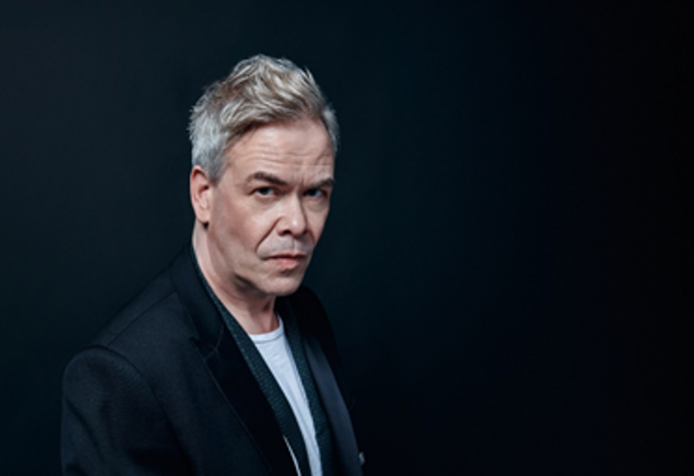 Kuvassa on Hannu Lintu puolivartalokuvassa ja tausta on tumma. 