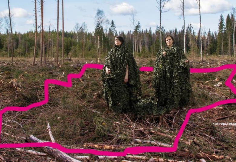 Kuvassa on metsänpohjaa ja siihen piirretty punainen alue.  Oikealla ylhäällä seisovat näyttelijät Marja Salo ja Hanna-Kaisa Tiainen. 