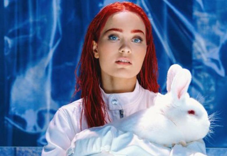 Kuvassa on Sanni valkoinen kani sylissään. Tausta on sininen.