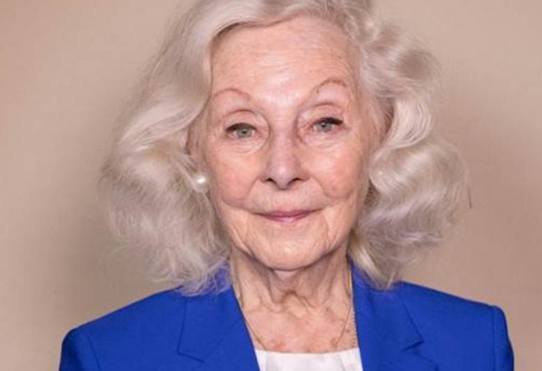 Kuvassa on Seela Sella kasvokuvassa ja sähkön sininen jakku sekä valkoinen toppi päällään.