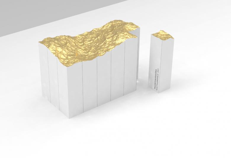 Kuvassa on Aallon kimallus -työ, jossa on valkoinen puolikuutio ja sen päällä on aaltomaista kultausta. Vieressä on pieni valkoinen pylväs, jossa on samantyyppinen kultaus ja muotoilu.