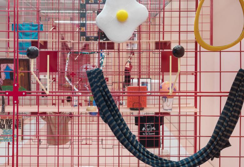 Kuvassa on punaista verkkoa, johon ripustettu erilaisia esineitä.