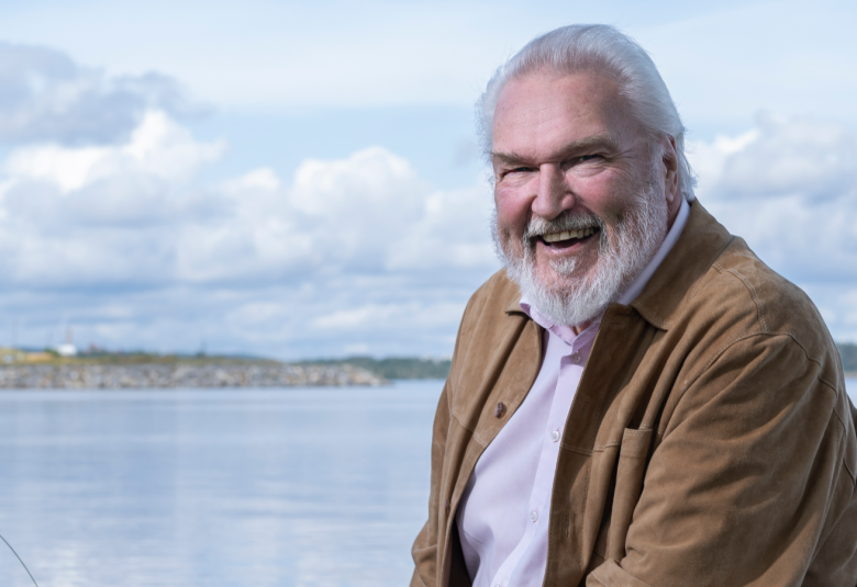 Kuvassa on puolivartalokuva Jaakko Ryhäsestä ja taustalla on järvenselkää sekä kauempana metsäistä rantaa.