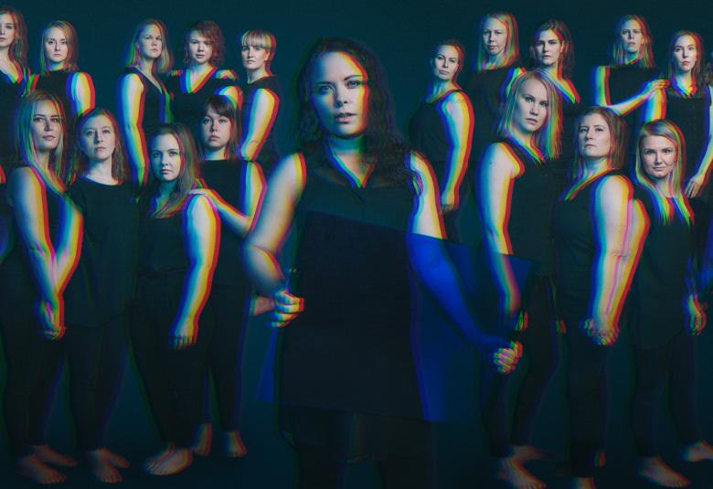 Kuvassa on Laulukollektiivi Sabrina ja Saarten tyttäret, jossa kuoro on yhteiskuvassa mustissa hihattomissa kuoroasuissa ja joillakin on sininen huivi.