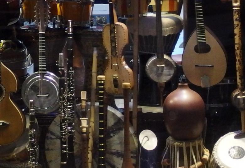 Kuvassa on tummalla pohjalla erilaisia soittimia.  Niiden sävy on ruskea.