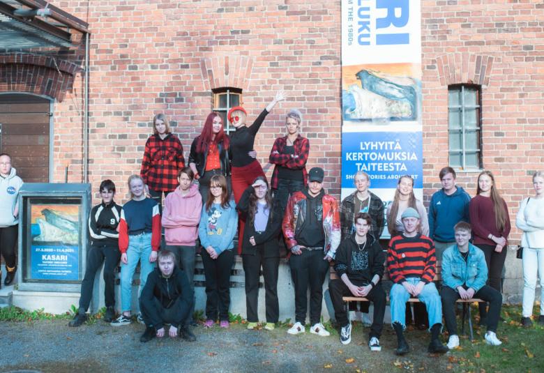 Kuvassa ovat näyttelyn taiteilijat ulkona ja taustalla on taidemuseon tiilinen seinä.