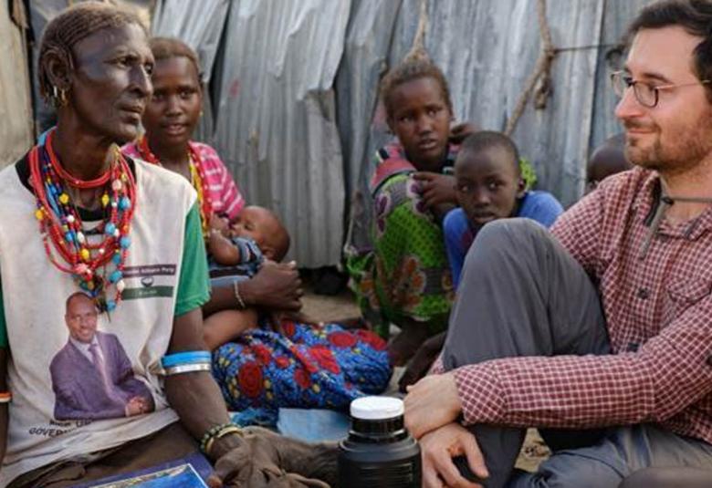 Kuvassa on vasemmalla afrikkalaisia ja suomalainen tutkija istumassa majassa ja keskustelemassa.