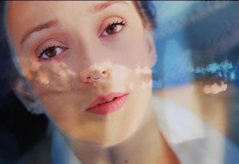 Kuvassa ovat Malla ollinin kasvot ja hänellä on mikki kädessään. Kuvaa on sävytetty vesimäisellä sinisellä kasvojen päälle. 