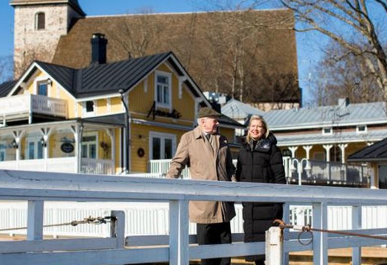 Kuvassa ovat Arto Noras ja Elina Vähälä sillalla taustallaan Naantalin kirkko.  Kuva on talvikuva.