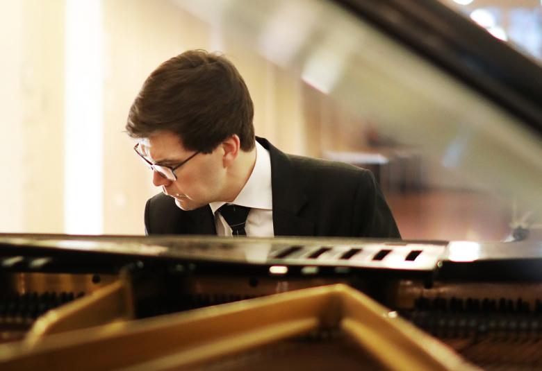 Kuvassa on Paavali Jumppanen soittamassa flyygeliä ja on kumartuneena kohti näppäimiä.