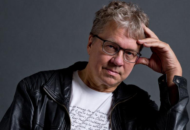 Kuvassa on Pekka Sauri, joka nojaa vasempaan käteensä istuessaan.