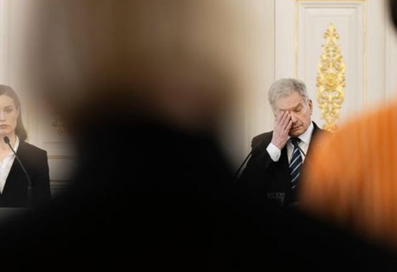 Kuvassa ovat vasemmalla Sanna Marin ja oikealla Sauli Niinistö istumassa. Kuvassa on henkilö seisomassa selin ja samalla erottaen Marinin ja Niinistön eri päihin pöytää.