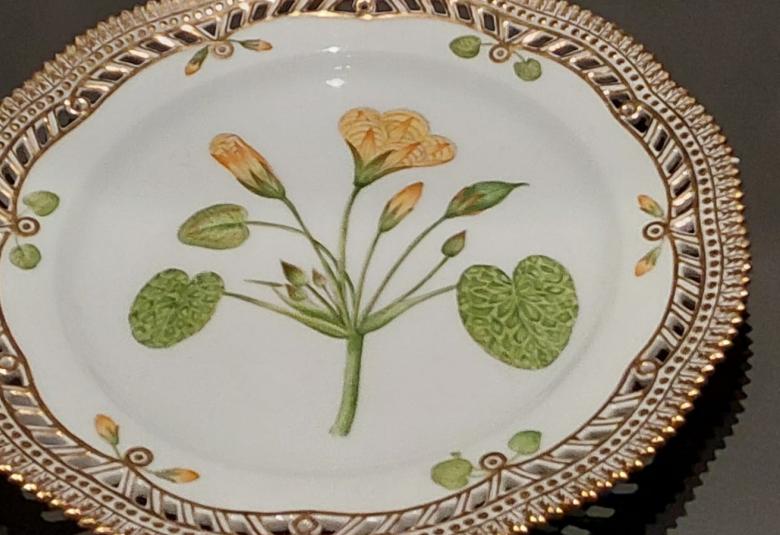 Kuvassa on vaalea lautanen, joissa on kukkakuvioita.