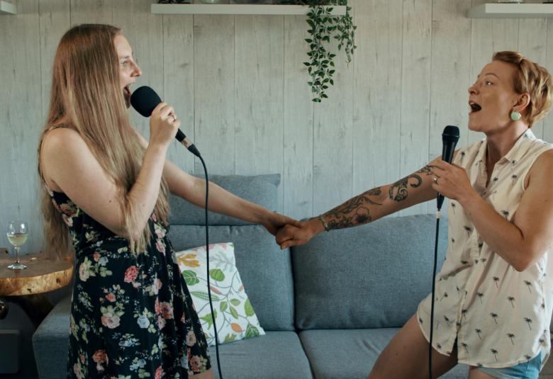 Kuvassa on kaksi nuorta naista laulamassa karaokea ja he ovat vastakkain.