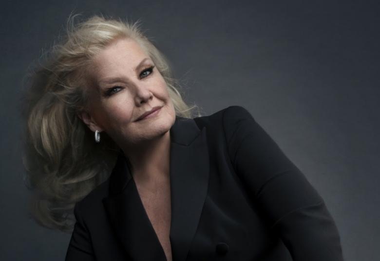 Kuvassa on Karita Mattila puolivartalokuvassa vonosti vasemmalle nojaten.  tauta on tumman harmaa ja Mattilan puku on musta.  Siinä on syvään uurrettu kaula-aukko.