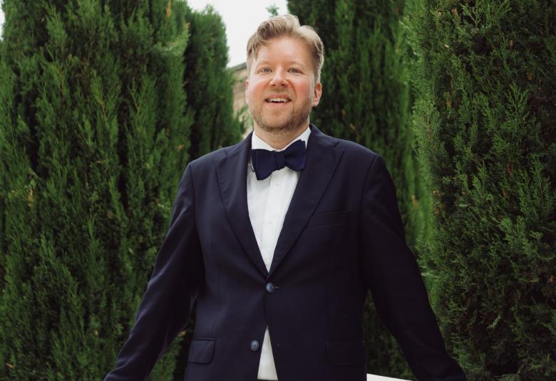 Kuvassa on Mikko Myllyllahti tummassa puvussa taustallaan sypressejä Cannesissa.