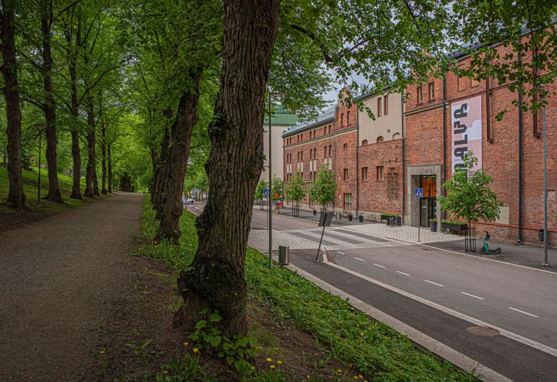 Kuvassa on punatiilinen Malskin rakennus ja katua, jossa on vihreitä puita.