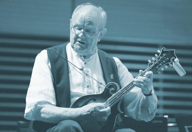 Kuvassa on Sauli Heikkilä soittamassa mandoliinia. Hän istuu ja mandoliini on hänen sylissään.