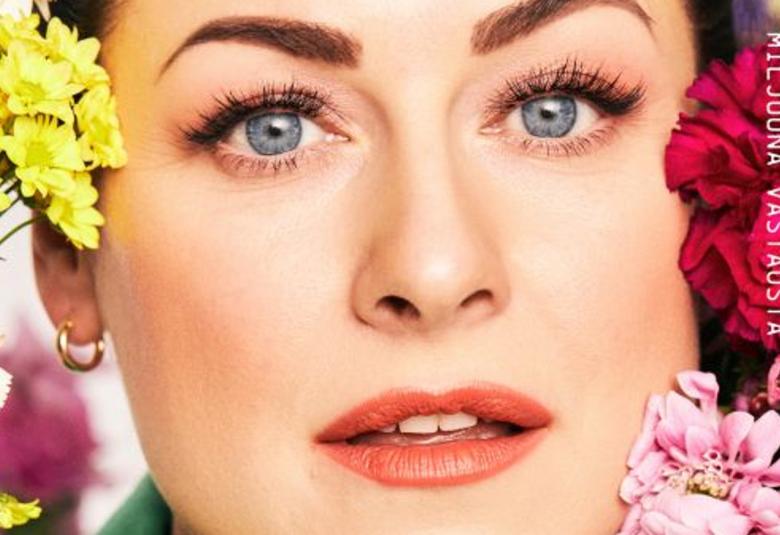 Kuvassa on Erin ja hänestä näkyy osa kasvoista otsasta leukaan.  Vasemmalla on pieniä keltaisia kukkia ja vasemmalla punaisia.