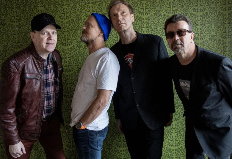 Kuvassa ovat Hassisen Koneen neljä jäsentä pusakoissa ja katsovat eri suuntiin eri asennoissa.