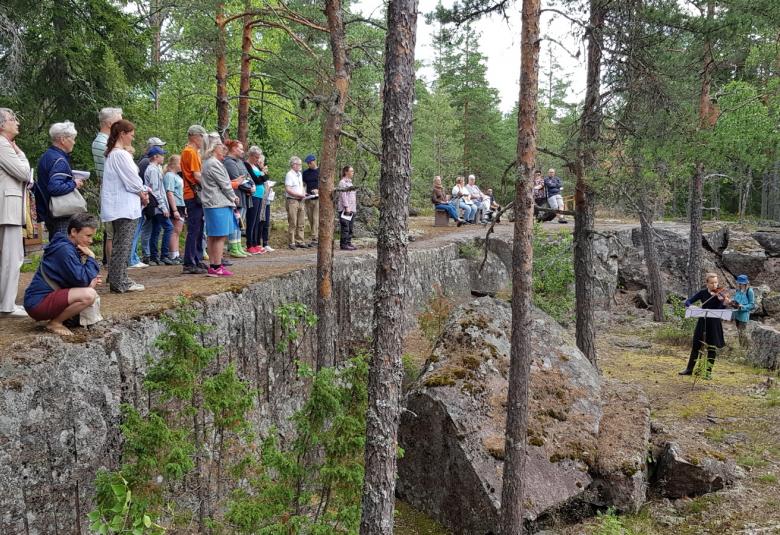 Kuvassa ovat oikealla alhaalla Pyterlahden louhistossa Viola Räisänen soittamassa viulua ja hänen takanaan Anni Kivimäki lukemassa tekstiään. Ylempänä pystysuoran kallion päällä on yleisöä nauhana kallion päällä.