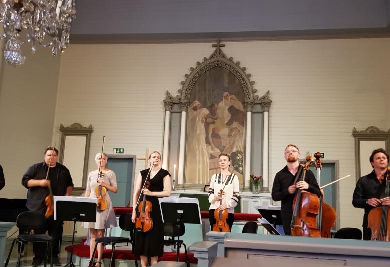 Kuvassa ovat Kaakon Kamarimusiikin soittajat kiittämässä konsertin jälkeen yleisöä.  Kuvassa on kähdeksan soittajaa ja puuttuu Jukka Merjanen.