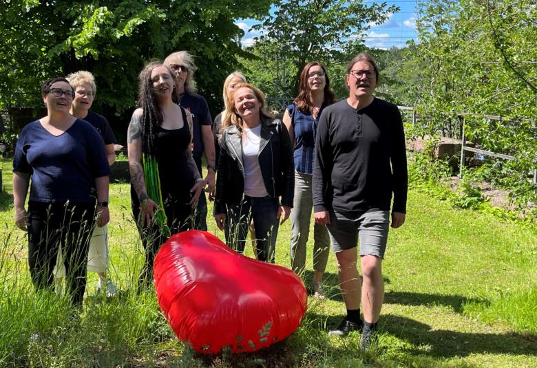 Kuvassa ovat Diakonissalaitoksen työntekijät 8 henkilöä, jotka laulavat videolla. He ovat kahdessa rivissä ja reunimmaisena oikealla edessä on yksi  mies ja muut ovat naisia.