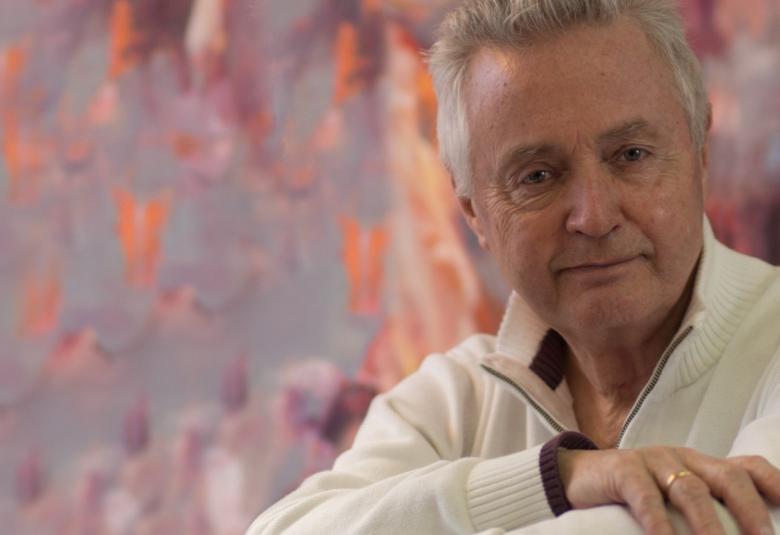 Kuvassa on Jukka Kuoppamäki puolivartalokuvassa istumassa valkoinen pusero päällään kuvan oikeassa reunassa.