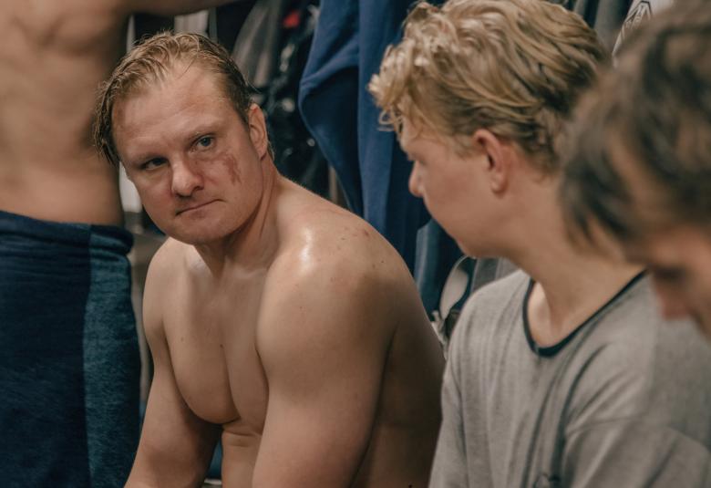 Kuvassa on Severi Saarinen ilman paitaa keskustelemassa vieruskaverinsa kanssa pukuhuoneessa.