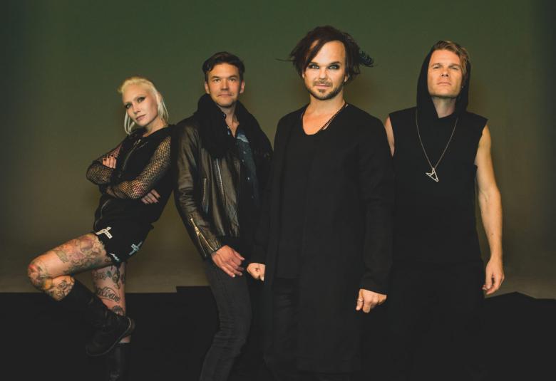 Kuvassa ovat The Rasmus -bändin jäsenet ja vasemmalla on bändin naisjäsen vinottain polvi koukistuneena seisomassa. Muut seisovat suorina ja kaikilla on mustat vaatteet. Tausta on ruskehtavan tumma.