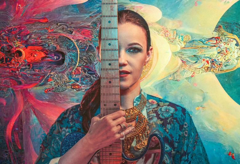 Kuvassa on keskellä Erja Lyytinen ja puolet kasvoista on näkyvissä. Oikealla on punasävyisiä suuriä viuhkoja ja takana on turkoosia ja keltaista.