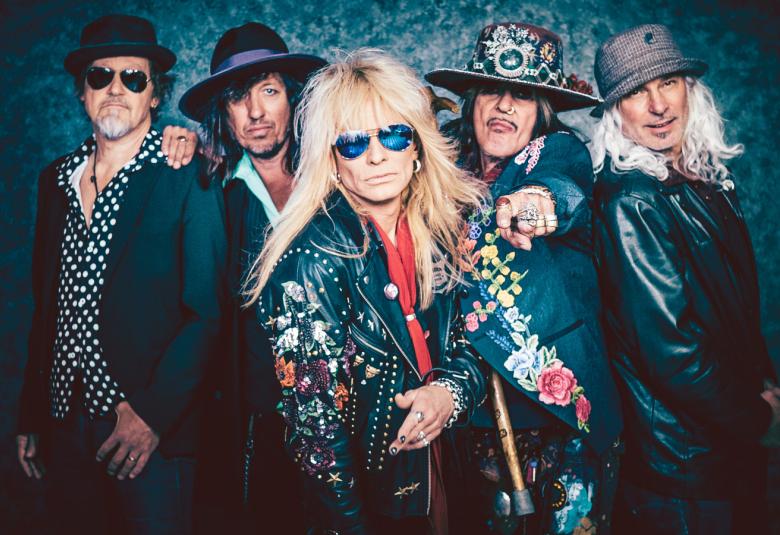 Kuvassa ovat Hanoi Rocksin viisi jäsentä ja Michael Monroe keskimmäisenä edessä.  Kaikilla on tummat takit ja erilaisia hattuja päässään. Tausta on tumma ja reunustaa bändiä.