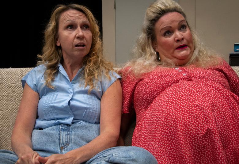 Kuvassa ovat Mira Helli risti-istunnassa sohvalla sinisissä vaatteissa ja oikealla Tanja Tuomi punaisessa mekossa.