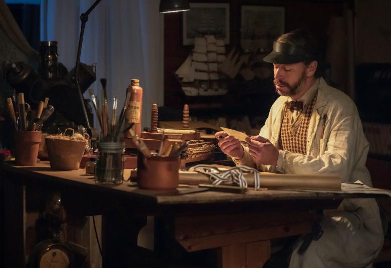 Kuvassa on Peter Franzen pöydän ääressä, jossa on paljon tavaraa ja ympäri koko huonetta.