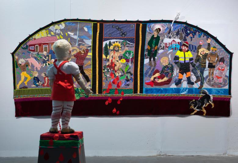 Kuvassa on pikku poika patsas punaisissa polvihousuissa katsomassa triptyykkiä seinällä. Vasemmalla on maatalon pihassa karkaava porsas. Keskesllä mies istumassa sädekehä päässään ja oikealla punaisen talon pihalla talon väkeä talvella.