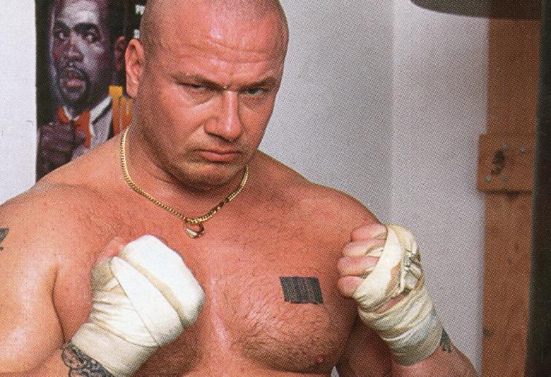 Kuvassa on Tony Halme lihaksikkaana ilman paitaa ja kädet edessä nyrkissä kämmenet valkoisissa siteissä.