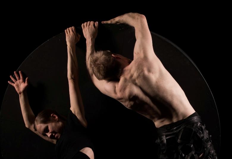 Kuvassa on kaksi tanssijaa hyppy asennossa selät vastakkain.  Heistä on puolivartalokuvat.